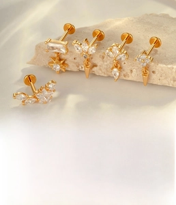 Detail of titanium alloy star cartilage studs with zircon on stone texture backdrop