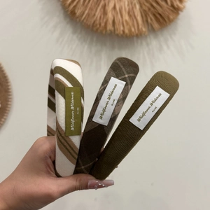Detailed close-up of three knitted headbands in olive green, plaid, and striped patterns