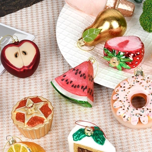 Hand-painted glass Christmas ornaments featuring fruit and dessert shapes on a white tray