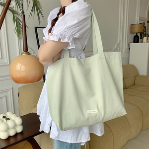 Large capacity mint green canvas tote bag shown on model in a modern home interior