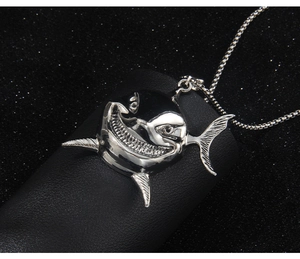 Macro detail of a silver shark pendant necklace featuring high-polished stainless steel metal