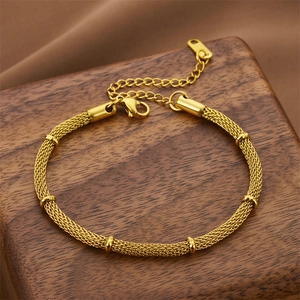 Gold mesh chain bracelet with cylindrical accents and adjustable lobster clasp on wood