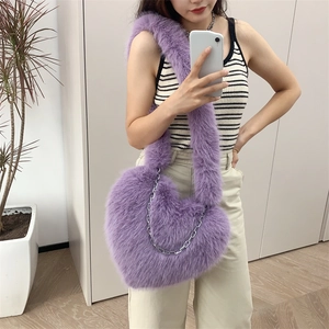 Macro shot of purple plush heart-shaped bag with soft faux fur and silver chain strap