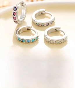Macro detail of copper silver-plated huggie earrings set with colorful opal inlay