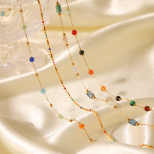 Gold chain necklace with colorful natural stone beads on smooth champagne silk fabric