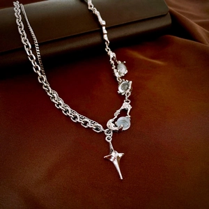 Detail of silver star pendant with light blue resin gemstone on silky dark fabric