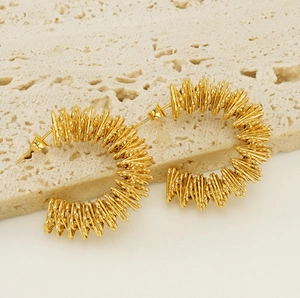 Detail of gold C-shaped earrings with intricate spiral wire texture and metallic finish