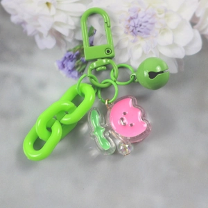 Detail of green plastic chain link and bell with pink cartoon loopy pendant accessory