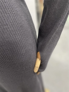 Detail of dark grey vertical ribbed knit fabric on long-sleeved elegant dress