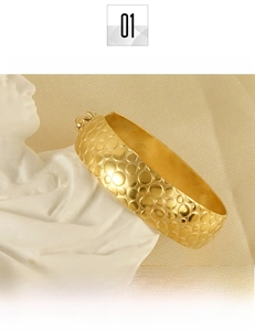 Detailed view of 18K gold plated titanium steel bangle with textured relief pattern