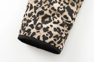 Close-up of leopard print fabric with quilted diamond stitching and black piping detail