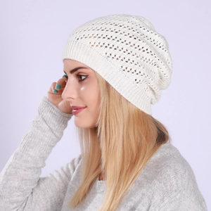Detail showing the intricate hollow-out knit pattern on a white slouchy beanie for winter