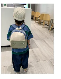 Rear view of child wearing a tricolor color-block canvas backpack with adjustable straps