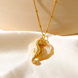 Gros plan du pendentif hippocampe doré avec incrustation de nacre sur un tissu soyeux