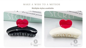 Close-up of hair claws in black and cream featuring glossy red heart-shaped embellishments