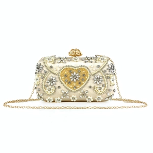 Detailed view of champagne evening clutch with pearl embroidery and golden heart buckle