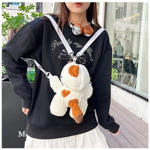 Outdoor shot of a plush calico cat crossbody bag with a heart pattern and adjustable strap