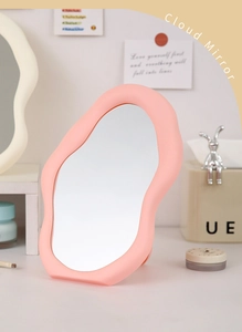 Close-up of pink cloud-shaped makeup mirror on a desktop with elegant decor