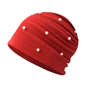 Detail of red knit beanie featuring white pearls and silver metal rivet decorations