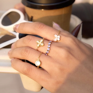 Detail of adjustable gold-plated rings with clover, butterfly, and purple zircon accents