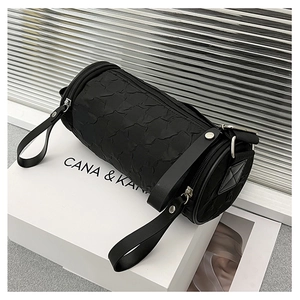 Close-up of black cylinder bag with pleated texture and silver rivet details