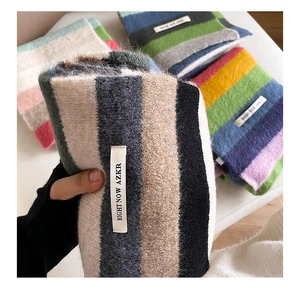 Close-up of rainbow mohair scarves showing fuzzy striped texture and sewn-in woven label
