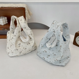 Detail of floral canvas wristlet bags with lace trim in cream and light blue tones