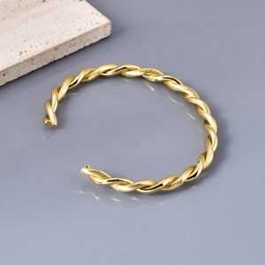 Macro shot of twisted golden titanium steel bangle with textured wire detail