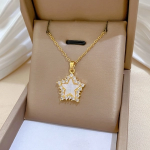 Macro view of gold star pendant with shell inlay and pavé crystals in a gift box