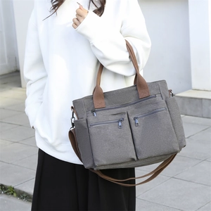 Graue Segeltuchtasche mit mehreren Taschen und braunen Trägern für den täglichen Pendelverkehr