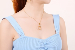 Close-up of model wearing gold layered necklace with circular zircon crystal pendants