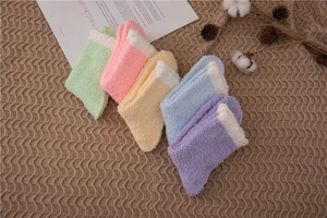 Macro view of five pastel coral fleece socks arranged neatly on a wavy brown textured rug