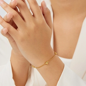 Detail of a minimalist gold heart bracelet with tiny crystals on a female wrist