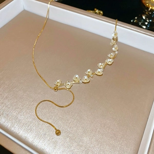 Dettaglio della collana a fiori dorati con perle centrali e chiusura a sfera regolabile