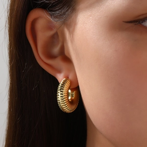 Detailed close-up of a gold croissant hoop earring with textured twisted design