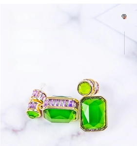 Macro detail of geometric drop earrings with emerald green and purple zircon stones