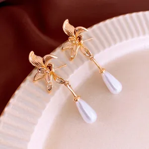 French style gold floral earrings with waterdrop pearls on elegant ceramic tray