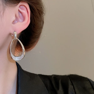 Detail view of model wearing silver teardrop earrings with pavé zircon accents