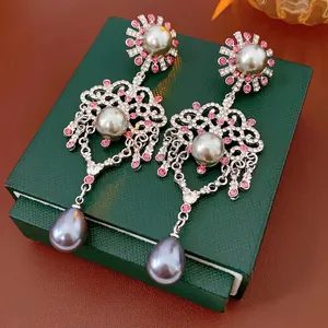 Vintage silver earrings with pink rhinestones and grey teardrop pearls on a jewelry box