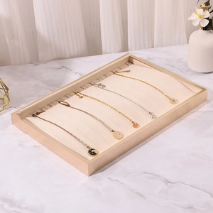 Detail view of a beige fabric jewelry tray with five necklaces displayed on hooks