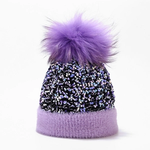 Close-up of purple knit winter hat with colorful sequins and a large faux fur pom-pom detail
