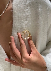 Detail of a 24k gold plated round brooch with pearls and zircons on a white sweater