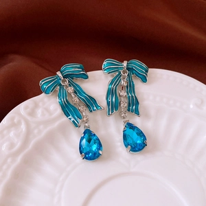 Detail of bow earrings with peacock blue teardrop crystals and sparkling accents