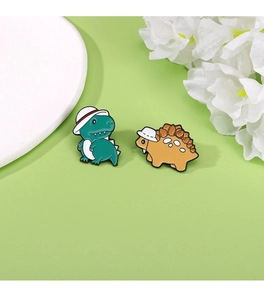 Detailed view of green and yellow enamel dinosaur pins with cute white hats on green background