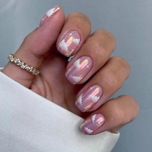 Macro detail of shimmer pink press-on nails with white cloud and star patterns