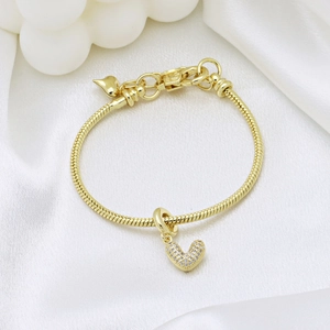 Elegant gold snake chain bracelet with sparkling crystal heart pendant on white silk