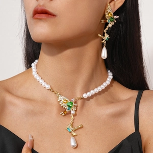 Detail of a pearl necklace set featuring a golden bird pendant with colorful gemstones