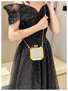 Octagonal gold mirror box bag with thin chain strap worn by model in elegant home setting
