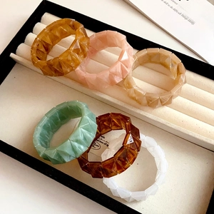 Set of six colorful geometric acrylic stretch bracelets with marbled texture in jewelry tray
