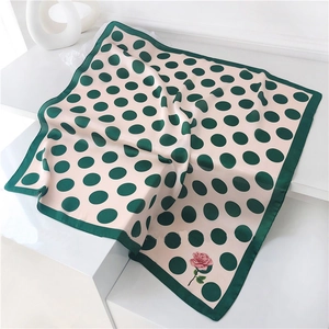 Detailed view of beige silk scarf with green polka dots and pink floral print accents